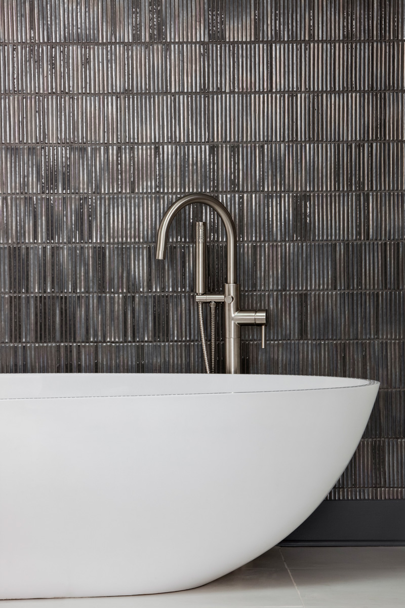 Modern bathtub and faucet with slate grey tiled wall